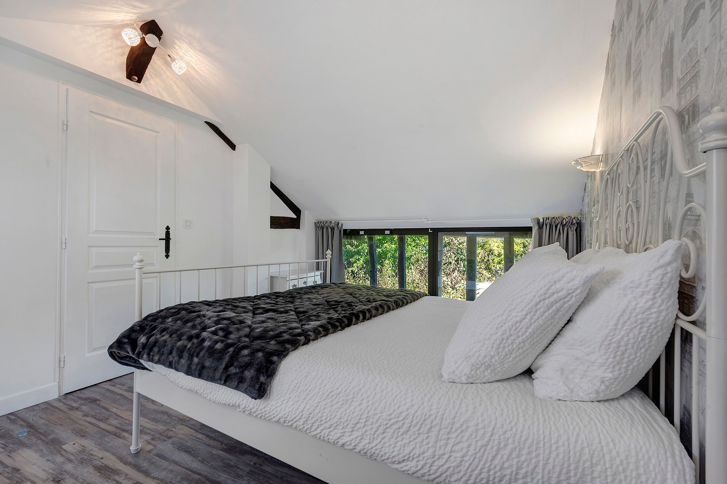 Une chambre à coucher avec un lit, une fenêtre avec des rideaux, une porte et un ventilateur de plafond.
