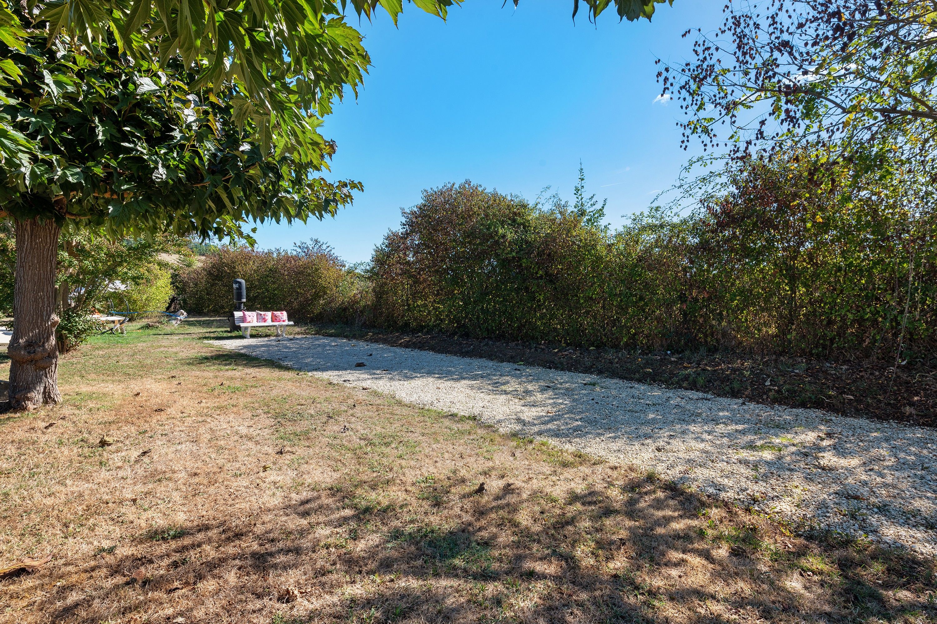 Ein Kiesweg schlängelt sich durch einen Park, gesäumt von Bäumen und Sträuchern.