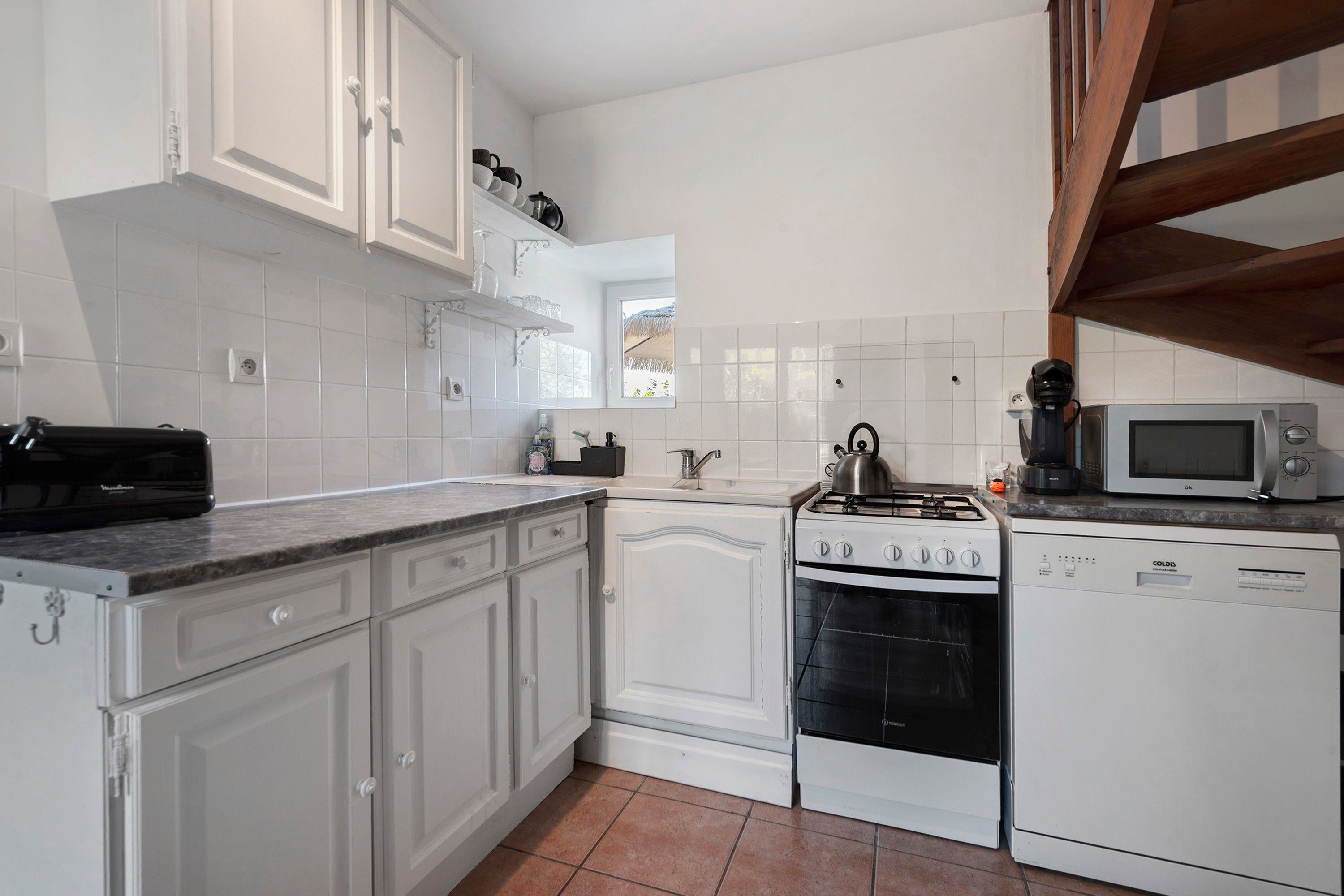 A kitchen with white cabinetry, a stove, a microwave, and a sink.