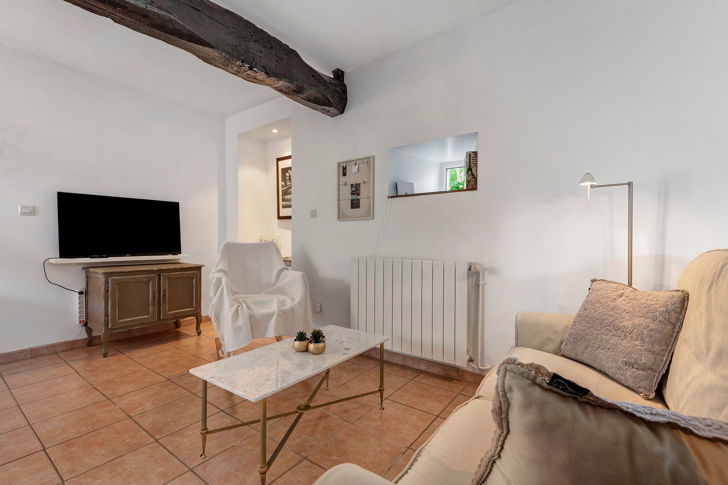 Een woonkamer met een televisie, een bank, een salontafel en een fauteuil.