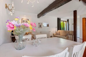 A dining area with a white table, chairs, a vase with flowers, and a chandelier. - Holiday Home “Domaine Logis Gascogne, Gîte 3” Mountain View, Pool & Wi-Fi (Saint-Justin)