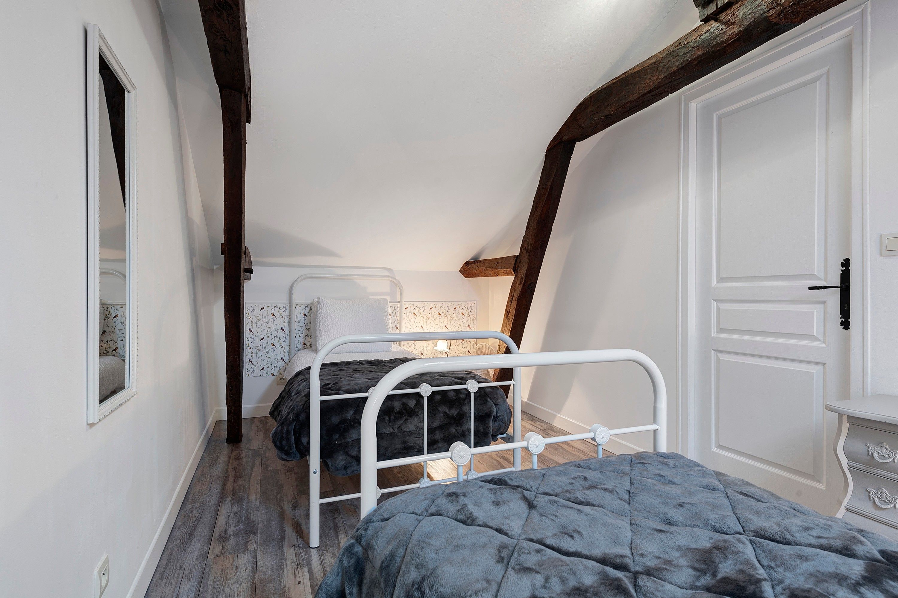 A narrow room with a bed, a wardrobe, and a mirror.