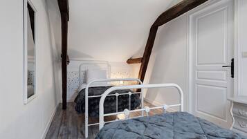 A narrow room with a bed, a wardrobe, and a mirror.