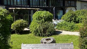 Un banc en bois dans un jardin, avec un bâtiment visible à l’arrière-plan.