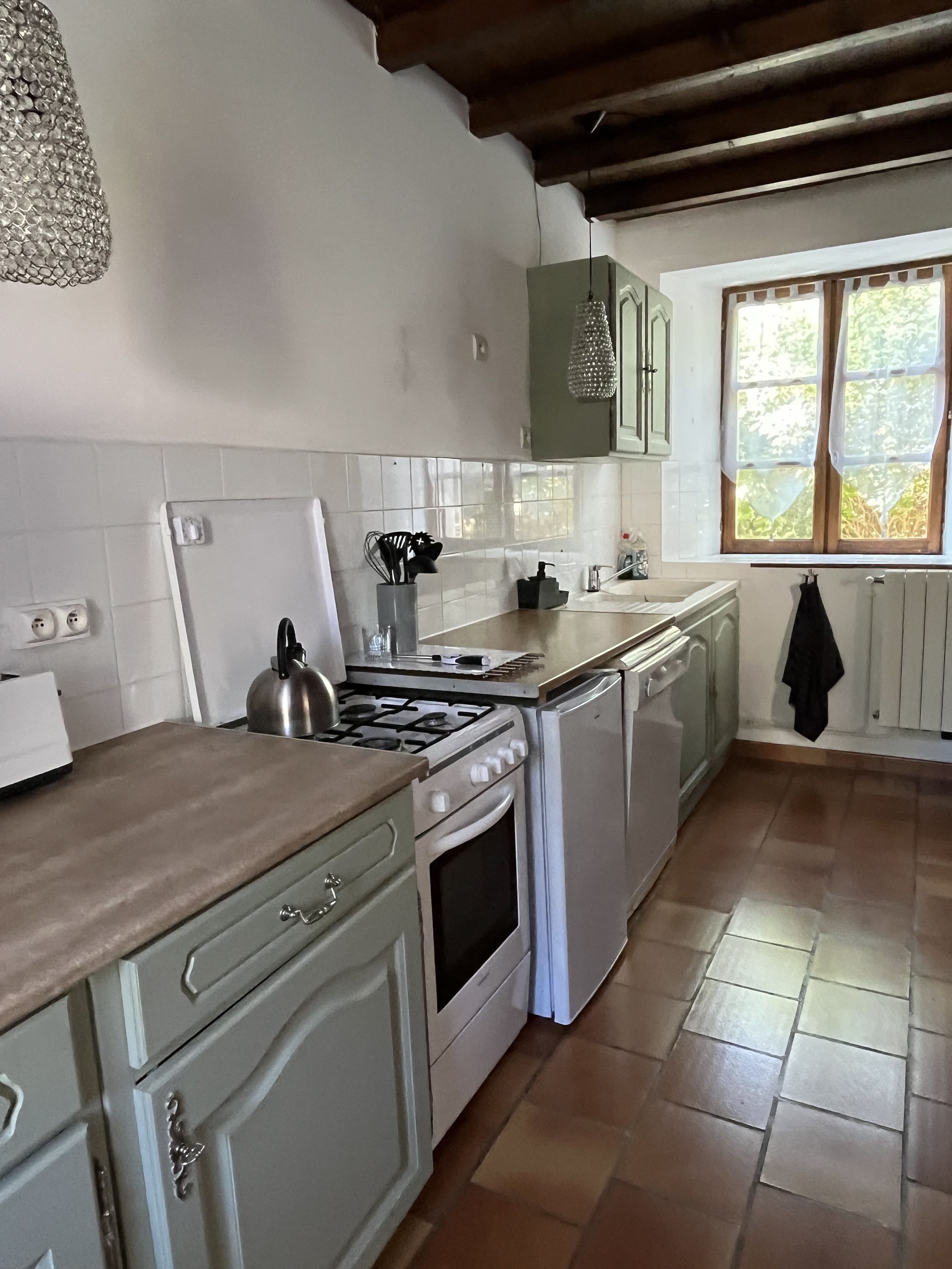 A kitchen with white cabinets, a stove, a sink, and a window with curtains.