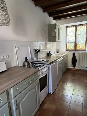 A kitchen with white cabinets, a stove, a sink, and a window with curtains. - Holiday Home “Domaine Logis Gascogne, Gîte 2”: Garden View, Pool, Wi-Fi (Saint-Justin)