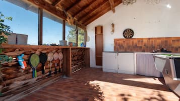 A rustic kitchen with wooden beams, a dartboard, and a variety of sports equipment.