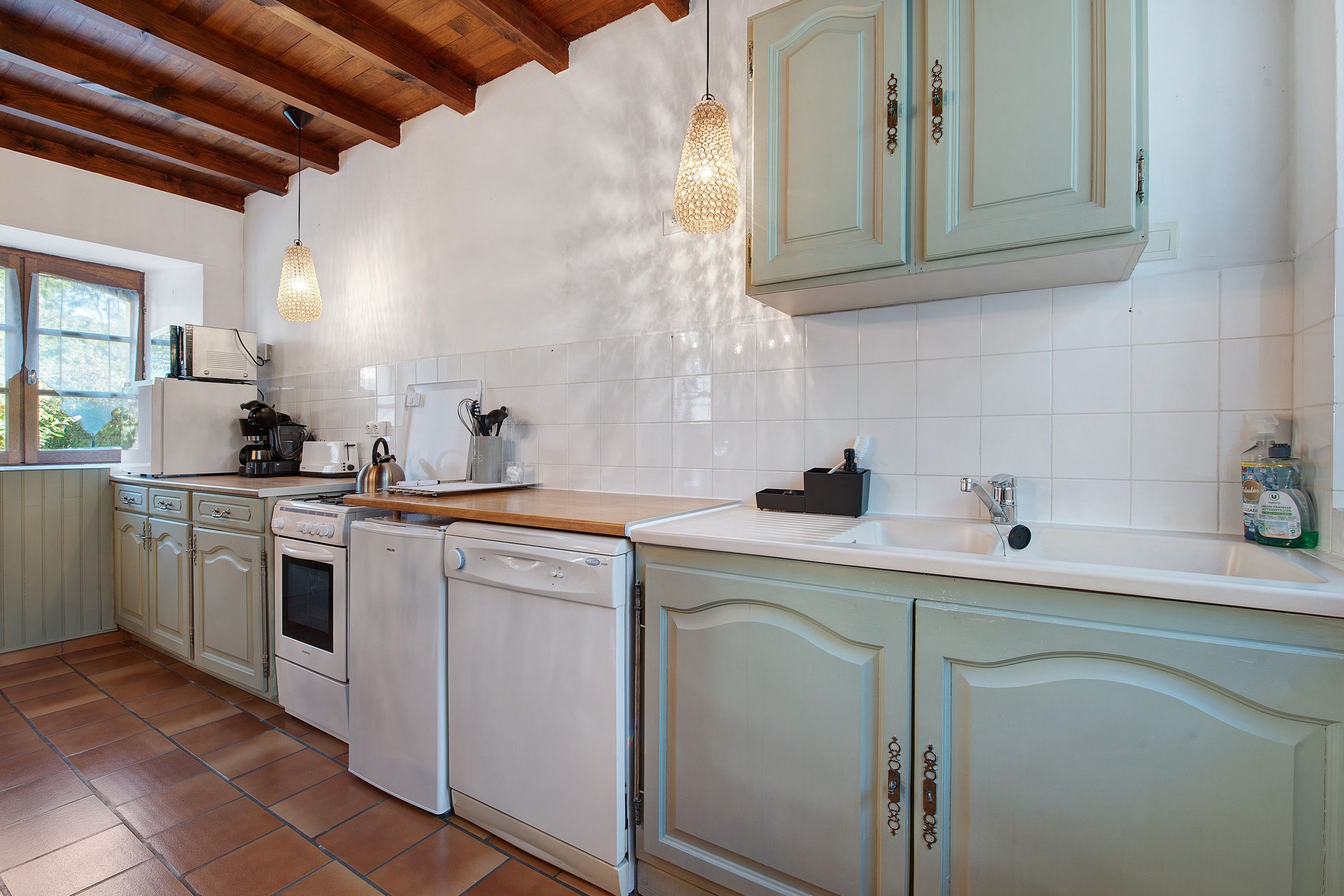 A kitchen with white cabinets, a wooden countertop, and a tiled backsplash.