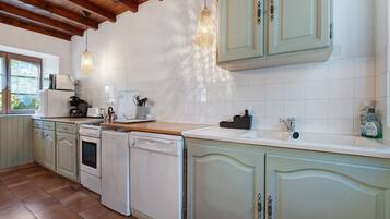 A kitchen with white cabinets, a wooden countertop, and a tiled backsplash.