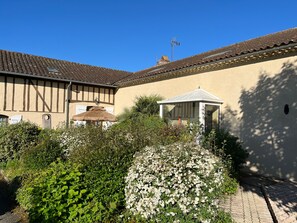 A traditional building with a thatched roof, a small garden with flowering plants, and a gazebo. - Holiday Home “Domaine Logis Gascogne, Gîte 2”: Garden View, Pool, Wi-Fi (Saint-Justin)