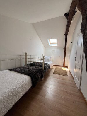 A bedroom with two beds, a skylight, wooden flooring, and a wardrobe. - Holiday Home “Domaine Logis Gascogne, Gîte 2”: Garden View, Pool, Wi-Fi (Saint-Justin)