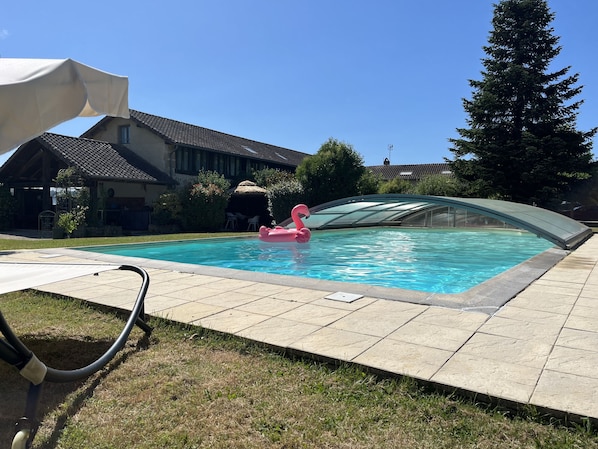 A swimming pool with a glass enclosure, a pink flamingo float, and a covered patio area. - Holiday Home “Domaine Logis Gascogne, Gîte 2”: Garden View, Pool, Wi-Fi (Saint-Justin)