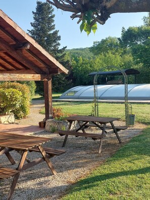 A covered outdoor area with picnic tables and a greenhouse in the background. - Holiday Home “Domaine Logis Gascogne, Gîte 2”: Garden View, Pool, Wi-Fi (Saint-Justin)