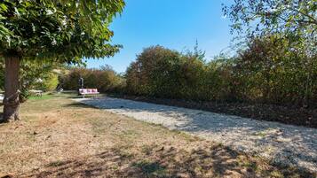 Uma trilha de cascalho serpenteia por um parque, ladeada por árvores e arbustos.