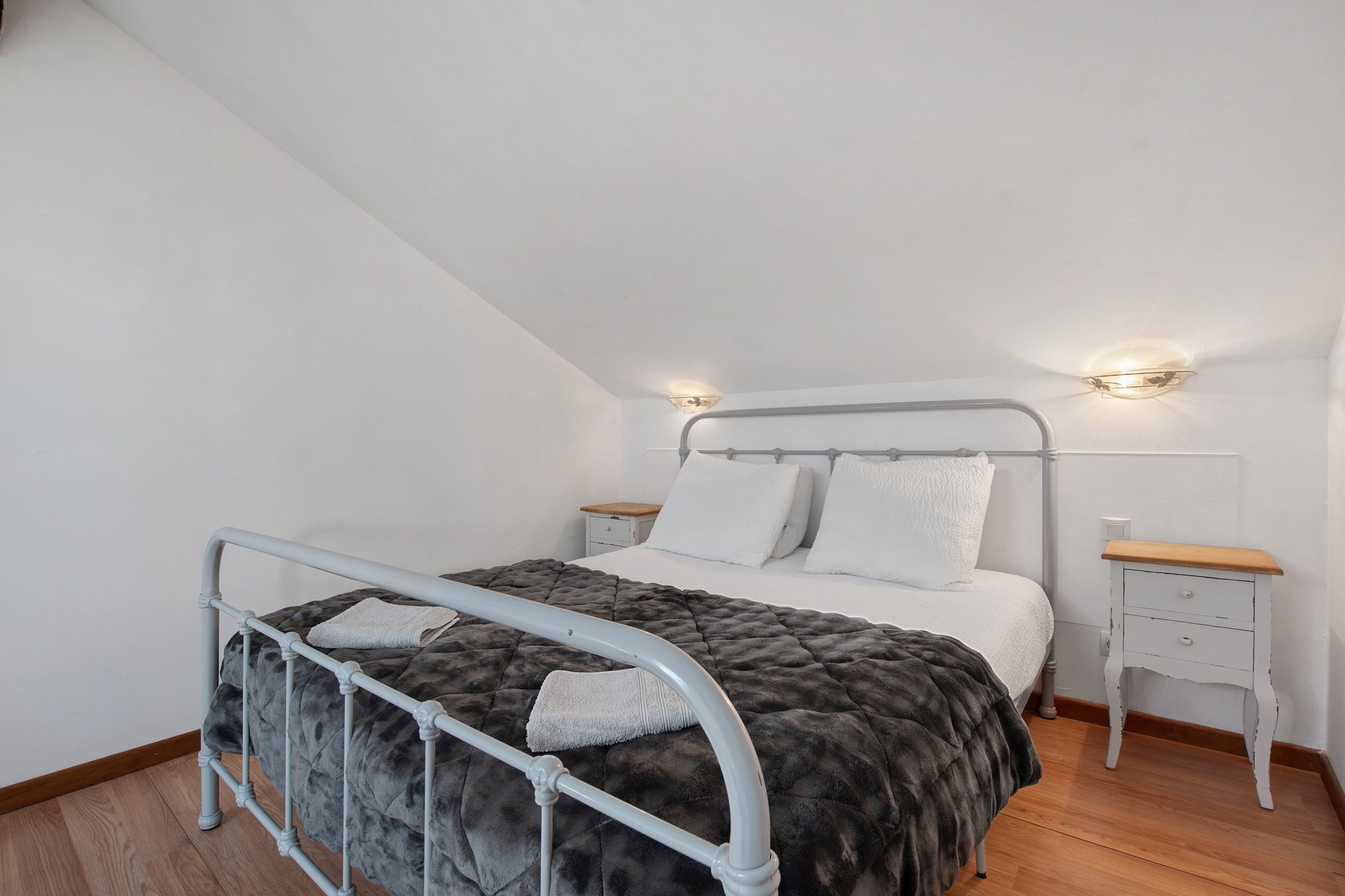 Een slaapkamer met een bed, nachtkastjes en een hoofdbord.