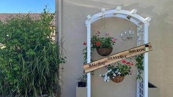 A welcome sign with a wooden archway, potted plants, and a clear blue sky.