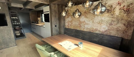 Cozinha moderna com bancada de madeira, forno embutido e luminária pendente.