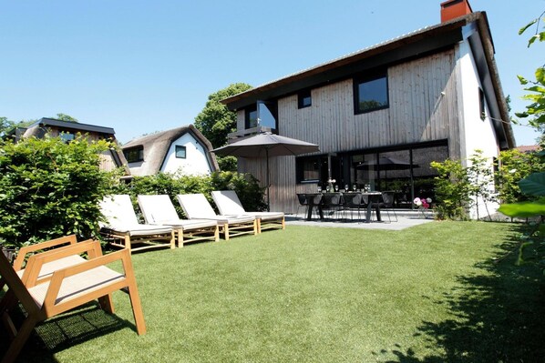 Un edificio moderno con un patio que incluye sillones y una mesa de comedor.