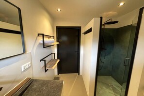 Un baño moderno con ducha, lavamanos y espejo.