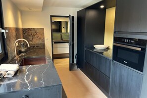 Cozinha moderna com bancada de mármore, forno embutido e pia com torneira.