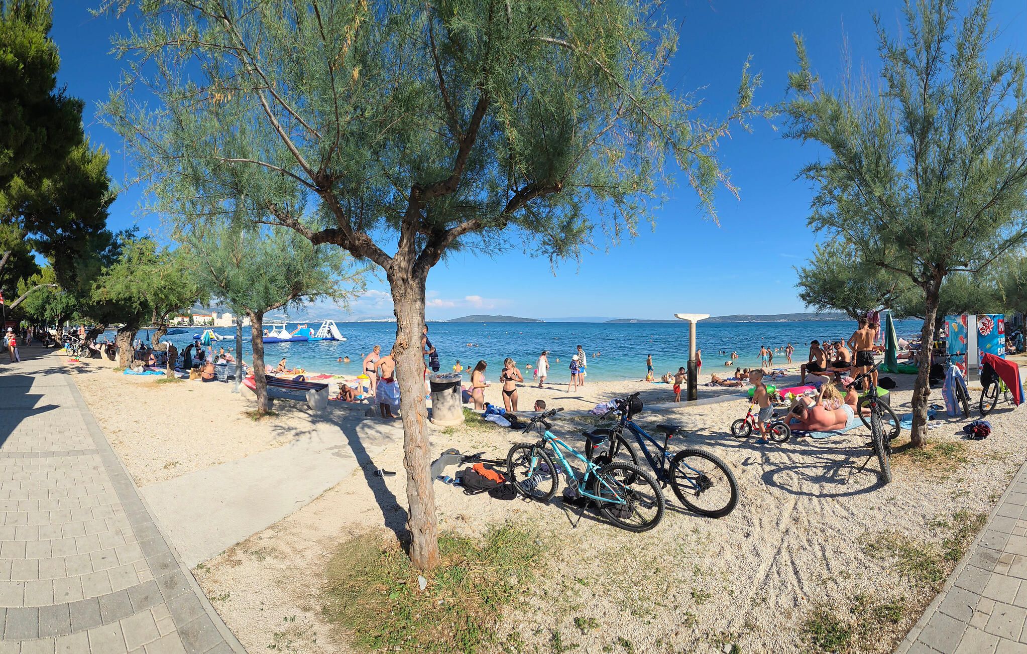 Une scène de plage avec des personnes, des vélos et un ciel dégagé.