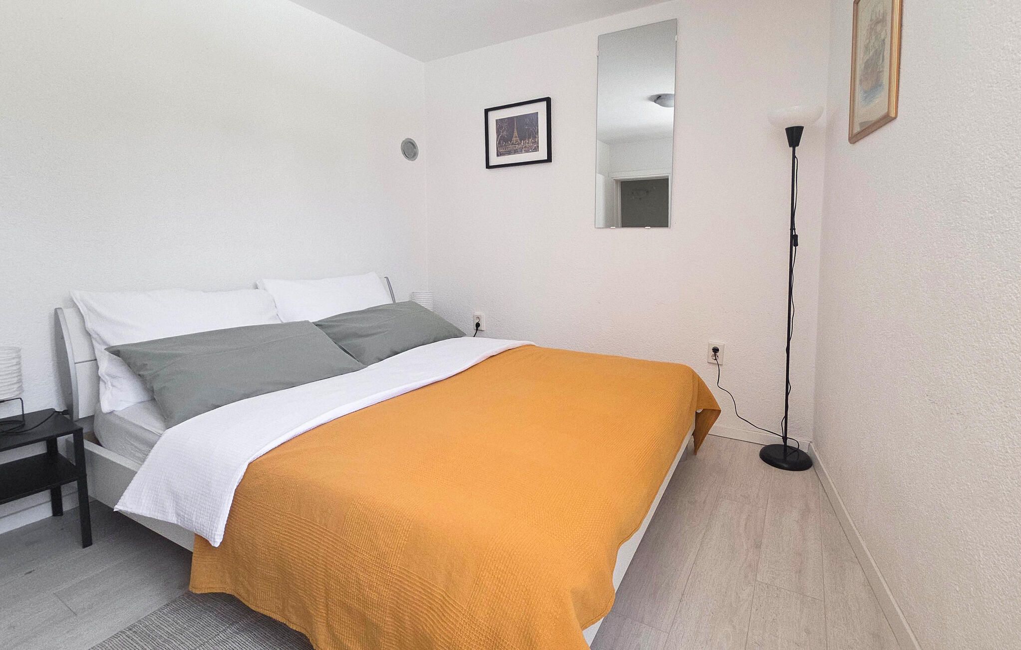 Une chambre à coucher avec un lit, une table de chevet, une lampe et un tableau encadré au mur.