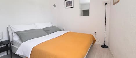 A bedroom with a bed, a nightstand, a lamp, and a framed picture on the wall.