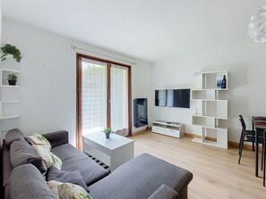 Ein modernes Wohnzimmer mit einem grauen Sofa, einem Flachbildfernseher und einer weißen Unterhaltungsanlage.