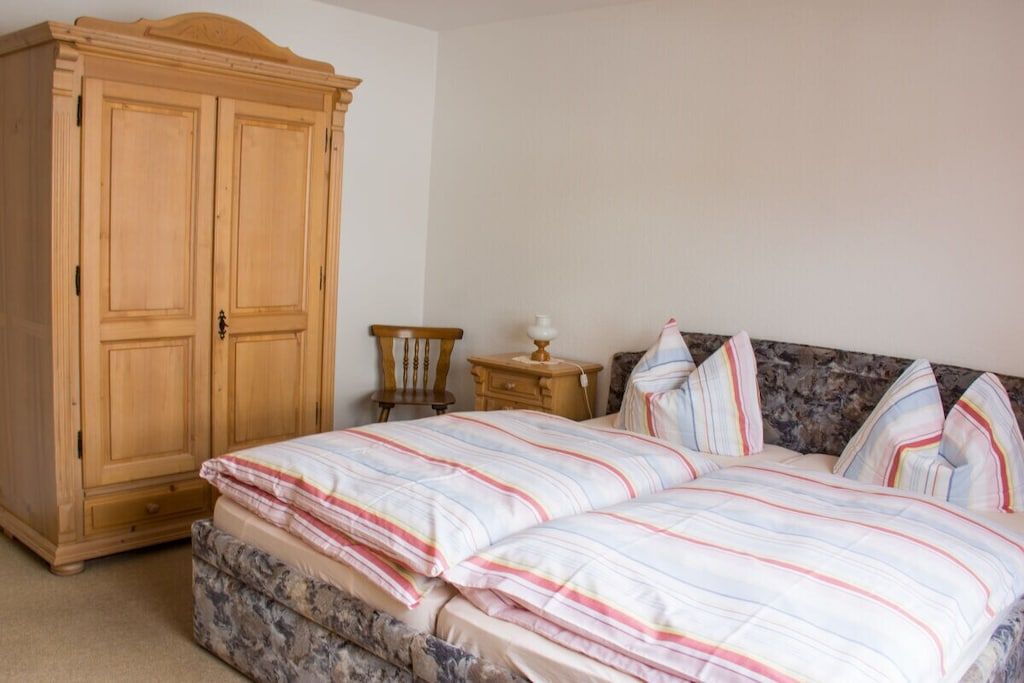 A bedroom with a bed, a wardrobe, and a nightstand.