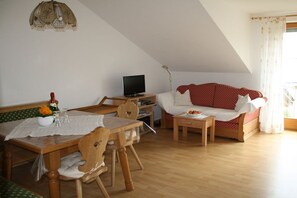 A cozy living room with a dining area, a television, and a sofa. - Holiday apartment with 3 bedrooms (Fürsteneck)