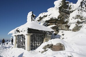 A snow-covered outdoor area with a stone structure, possibly a monument, and a plaque. - Holiday apartment with 3 bedrooms (Fürsteneck)