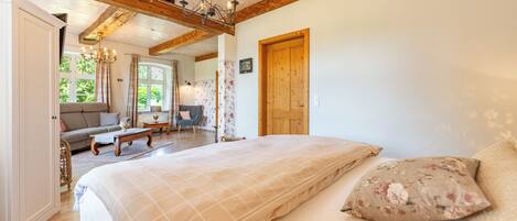 Un dormitorio con una cama grande, vigas de madera, una araña y vistas al exterior.
