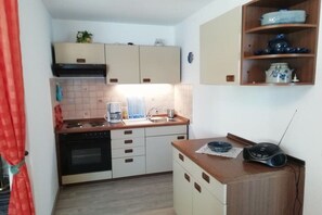 A compact kitchen with a stove, sink, and a radio on a wooden counter. - Holiday apartment with 2 bedrooms (Oberreute.)