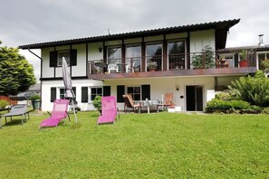 A two-story house with a balcony, a lawn, and outdoor furniture. - Holiday apartment with 2 bedrooms (Oberreute.)