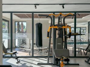 Une salle de sport équipée de matériel d’exercice, d’un sac de frappe et d’un banc.