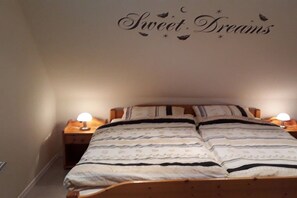 A bedroom with a bed, two bedside tables with lamps, and a wall decoration that reads 'Sweet Dreams'. - Holiday apartment with 2 bedrooms (Bispingen)