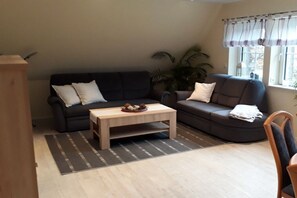 A living room with two sofas, a coffee table, and a window with curtains. - Holiday apartment with 2 bedrooms (Bispingen)