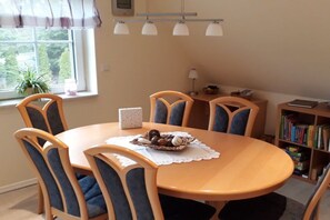 A dining area with a round table, four chairs, a small decorative bowl, and a bookshelf in the background. - Holiday apartment with 2 bedrooms (Bispingen)