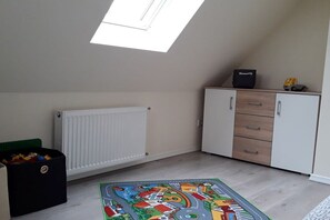 A child's playroom with a skylight, a radiator, a cabinet with drawers, and a colorful play mat. - Holiday apartment with 2 bedrooms (Bispingen)