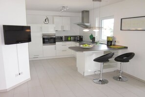 A modern kitchen with white cabinetry, stainless steel appliances, and a central island with bar stools. - "On the banks of the Moselle in Bernkastel" (Bernkastel-Kues)