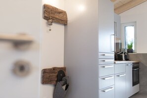 A modern kitchen with white cabinetry, a wooden wall-mounted towel rack, and a pair of slippers. - Holiday apartment with 1 bedroom (Garmisch-Partenkirchen)