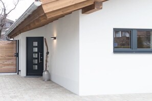 A modern building with a black door, a window, and a wooden overhang. - Holiday apartment with 1 bedroom (Garmisch-Partenkirchen)