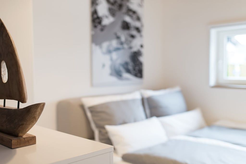 Ein Schlafzimmer mit Bett, Kissen, einem Nachttisch und einem an der Wand hängenden Kunstwerk.