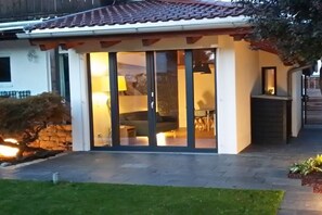 A modern house with a glass door entrance, a stone wall, and a well-maintained garden. - Holiday apartment with 1 bedroom (Garmisch-Partenkirchen)