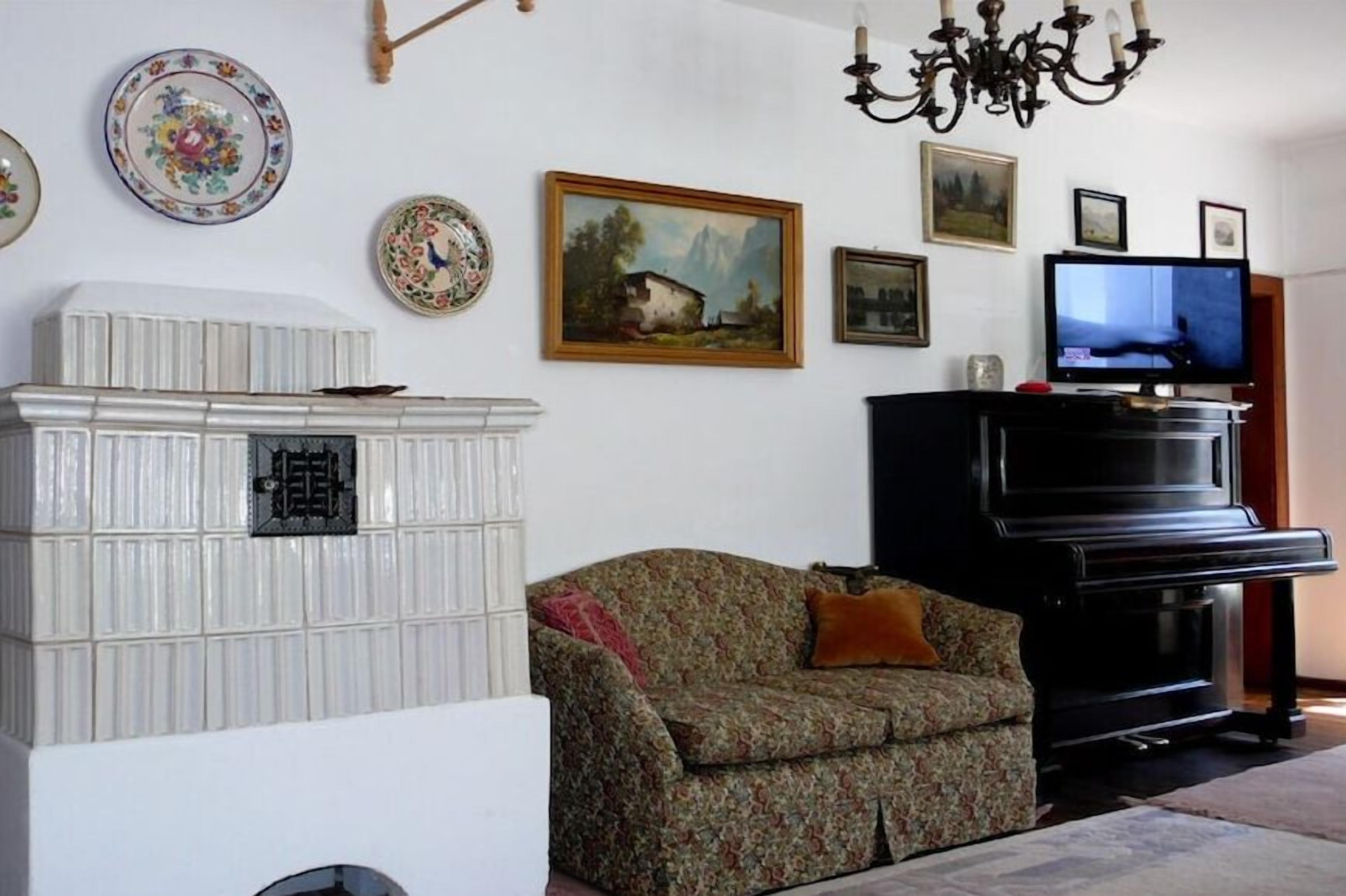 Un salon avec un canapé, un téléviseur, un piano et des assiettes décoratives accrochées au mur.