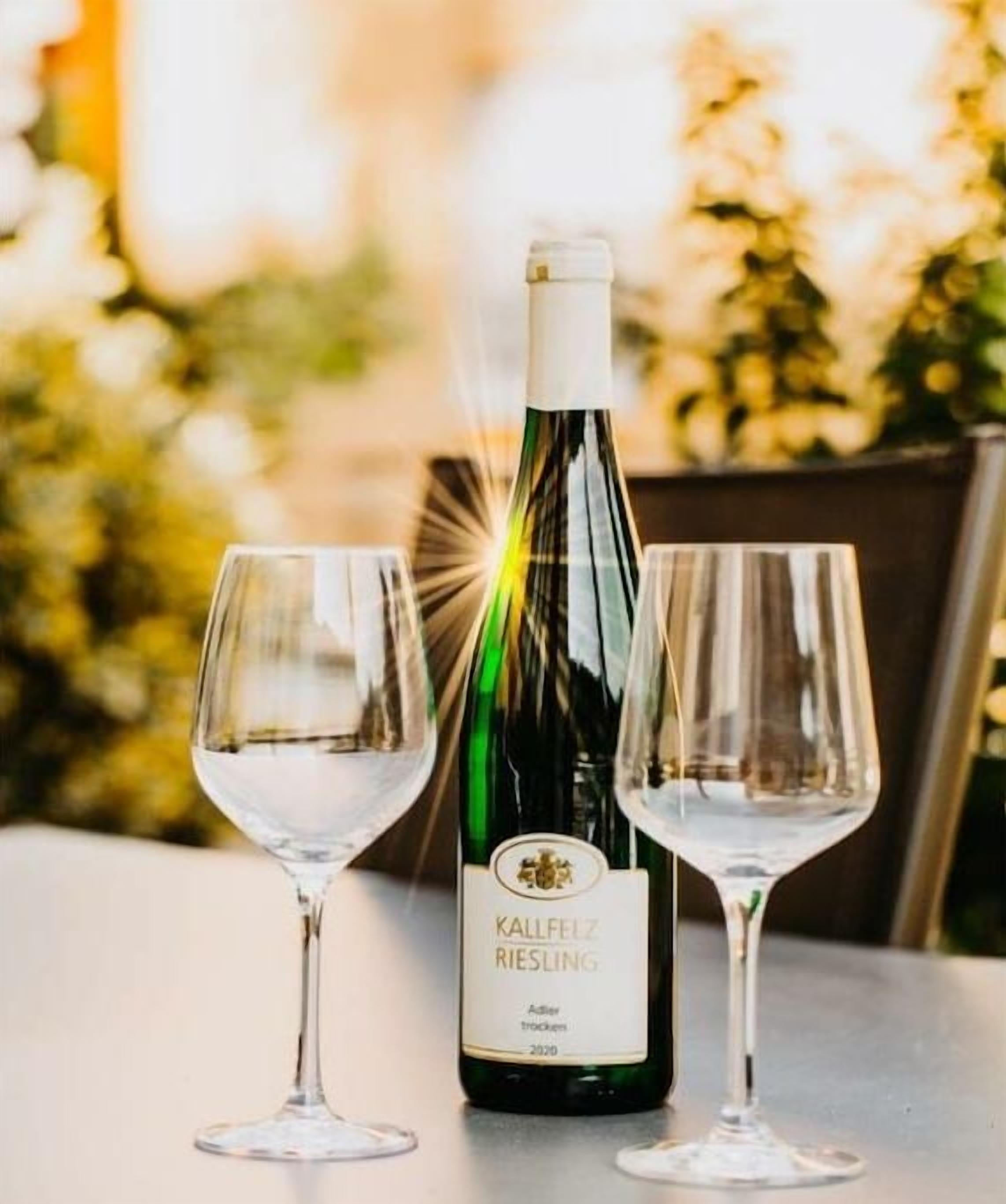 A bottle of Kallfelz Riesling wine with two empty glasses on a table.