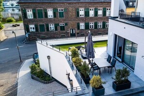 En moderne bygning med en patio med udendørs siddepladser og plantekasser.