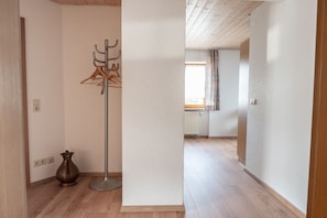 A hallway with a coat rack, a floor lamp, and a vase on the floor. - House with a view of the church (Schliengen-Mauchen)