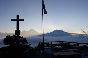 A cross, a flag, and a mountainous landscape with a wooden fence and seating area. - Holiday apartment with 1 bedroom (Bischofswiesen)