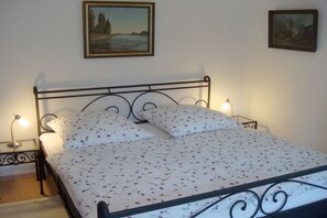 A bed with a metal frame, two bedside tables with lamps, and two framed pictures on the wall. - Holiday apartment with 1 bedroom (Bischofswiesen)